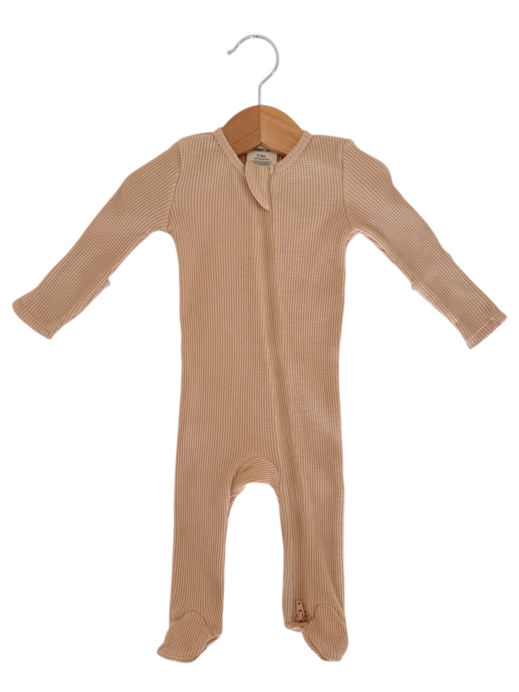 Beige baby onesie on a wooden hanger with long sleeves and a front zipper.