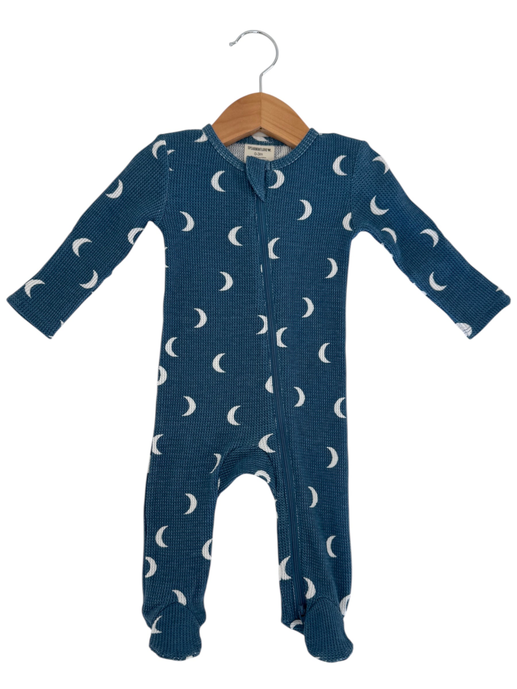 Blue baby onesie with moon pattern, hanging on a wooden hanger.