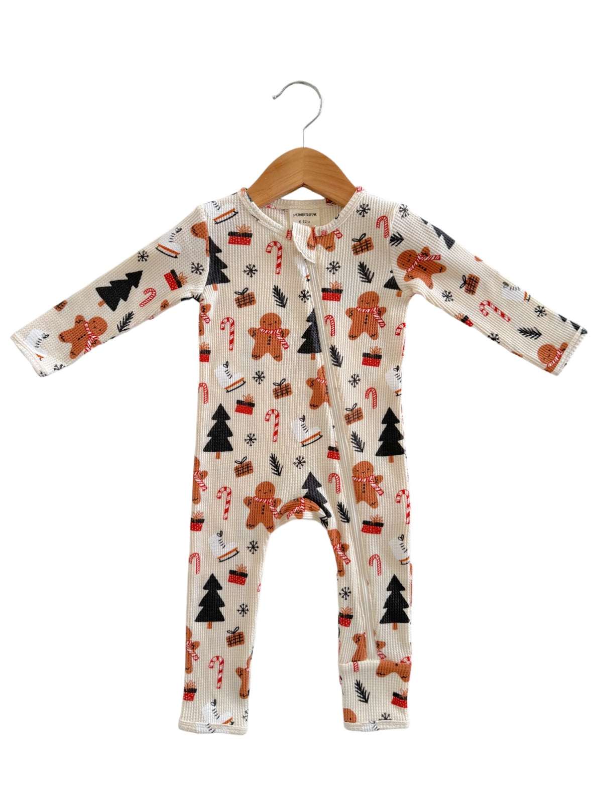 Gingerbread-themed baby onesie with holiday patterns, hanging on a wooden hanger.