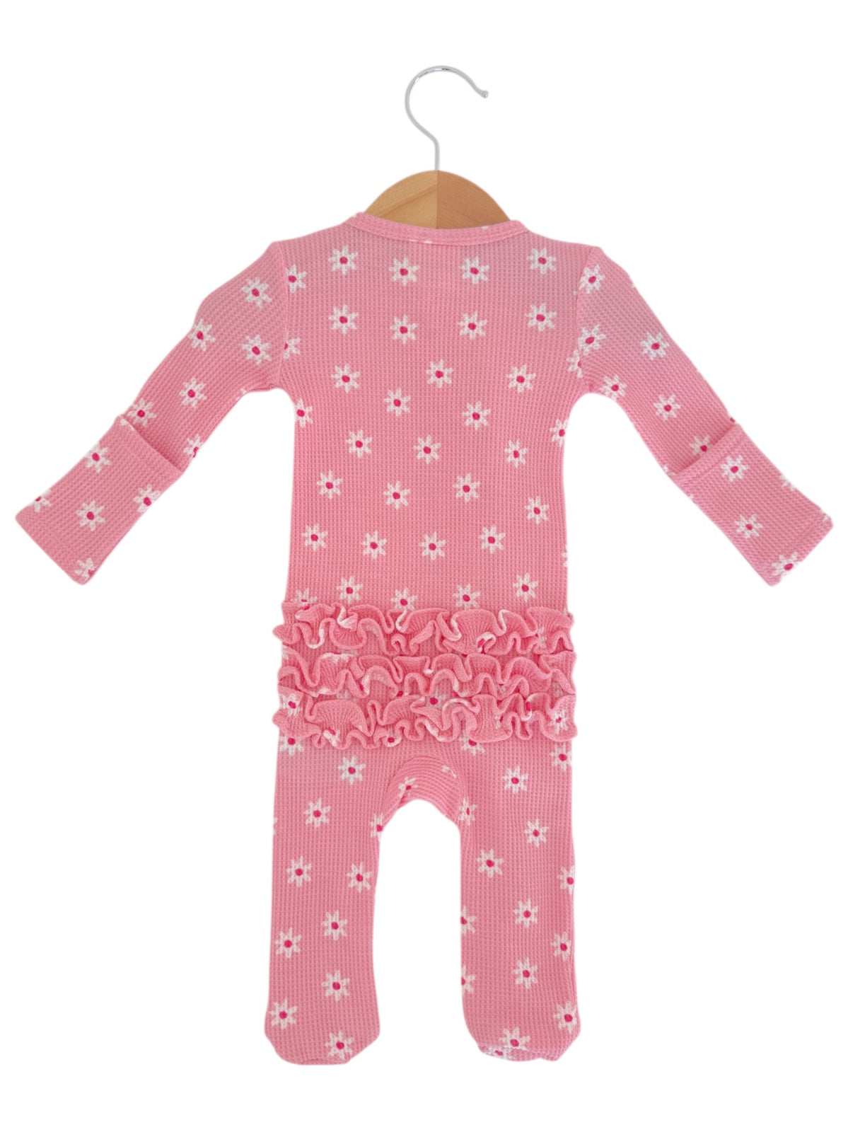 Pink baby romper with flower pattern and ruffle details, hanging on a wooden hanger against a white background.