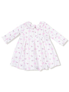 White dress with pink floral and bow print, featuring long sleeves and a rounded collar.