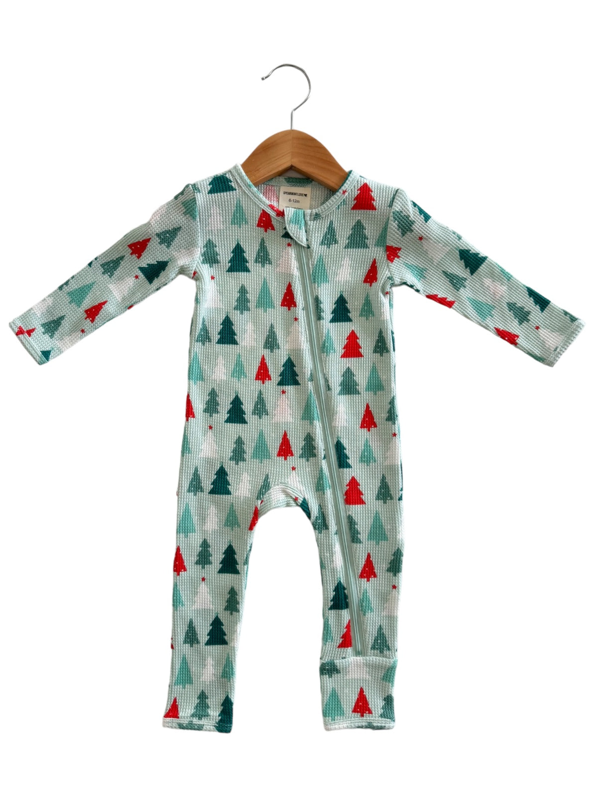 Long-sleeve baby onesie featuring a festive pine tree print in green and red, displayed on a wooden hanger.