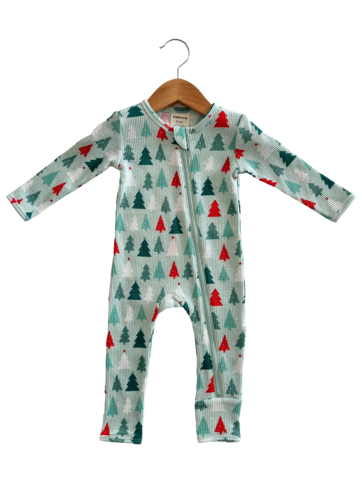 Long-sleeve baby onesie featuring a festive pine tree print in green and red, displayed on a wooden hanger.