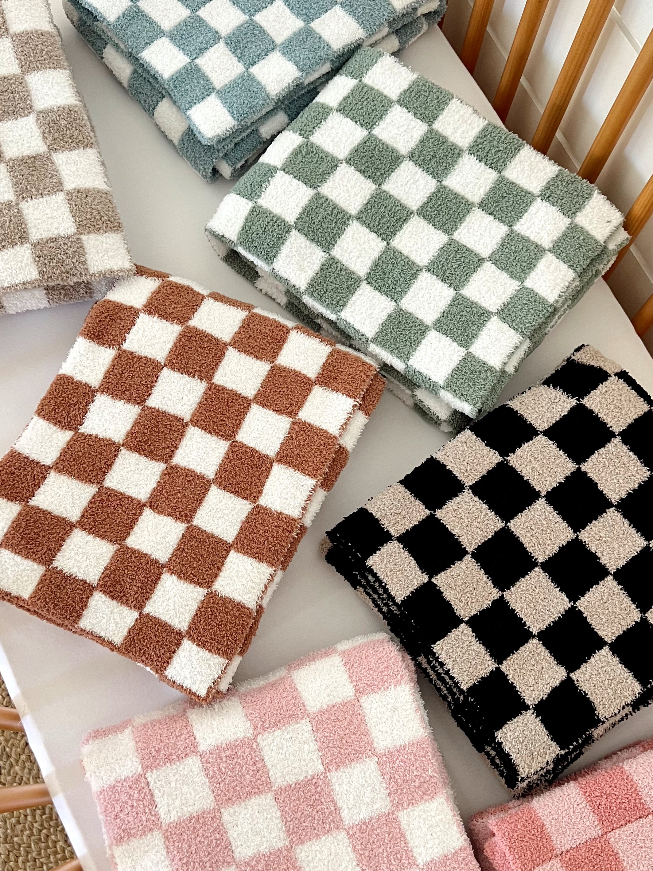Colorful checkered towels stacked on a table in various shades, showcasing their soft texture and patterns.