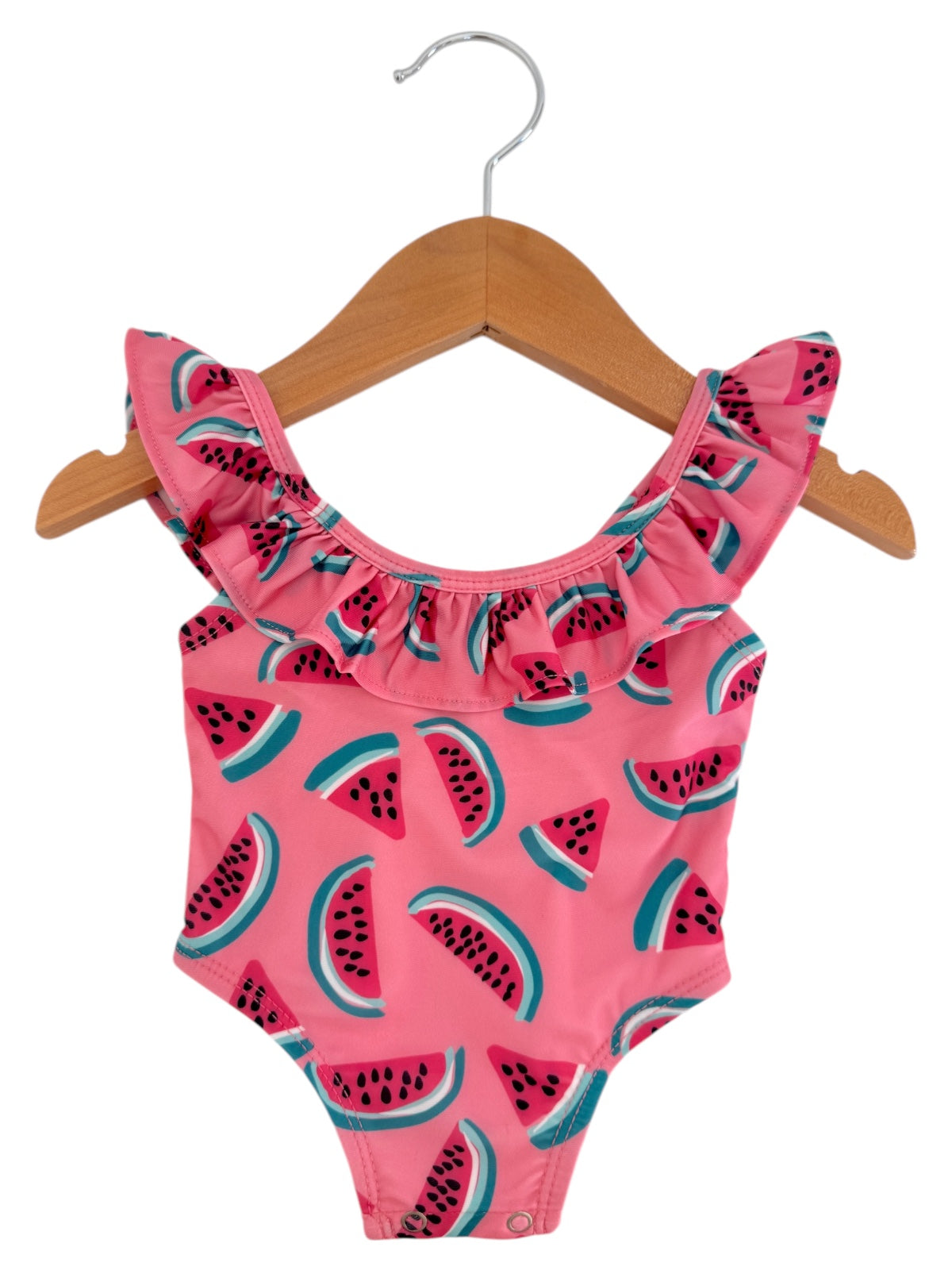 Pink swimsuit with watermelon pattern and ruffled straps, displayed on a wooden hanger. Perfect for summer fun.