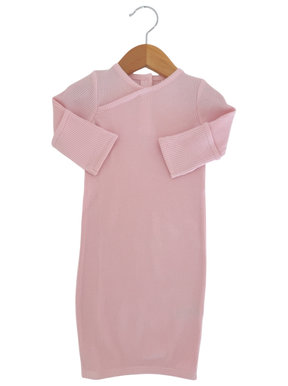 Pink baby dress with ribbed texture, displayed on a wooden hanger against a white background.
