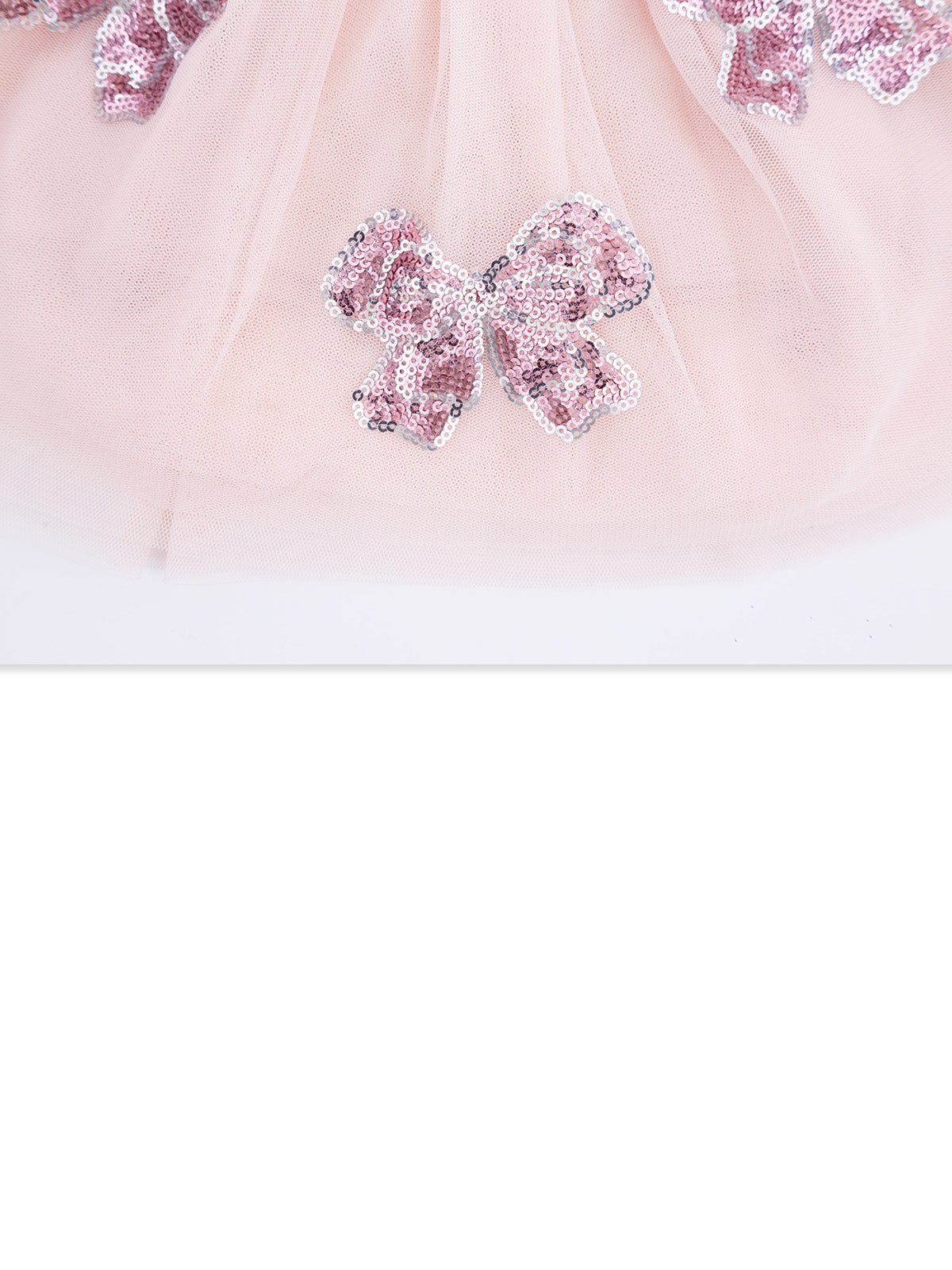 Pink tulle fabric adorned with shiny sequined bows. Elegant and playful design for children's wear.