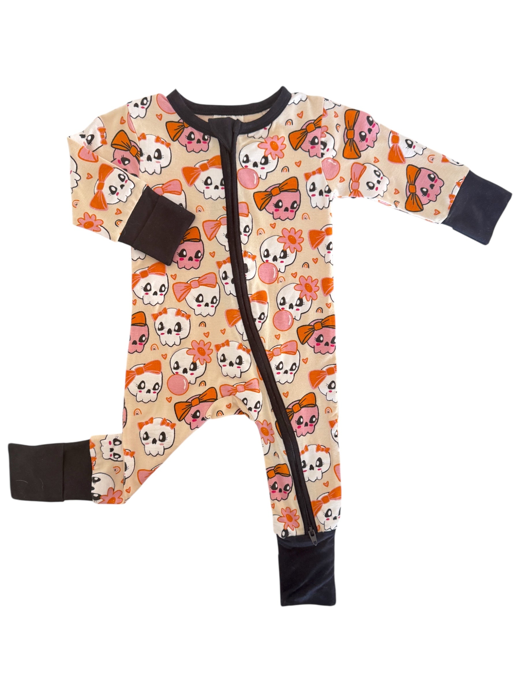 Toddler onesie featuring a playful skull and bow pattern in pastel colors on a cream background.