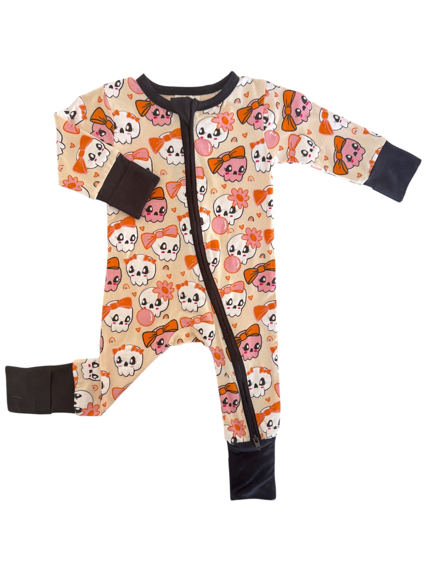 Toddler onesie featuring a playful skull and bow pattern in pastel colors on a cream background.