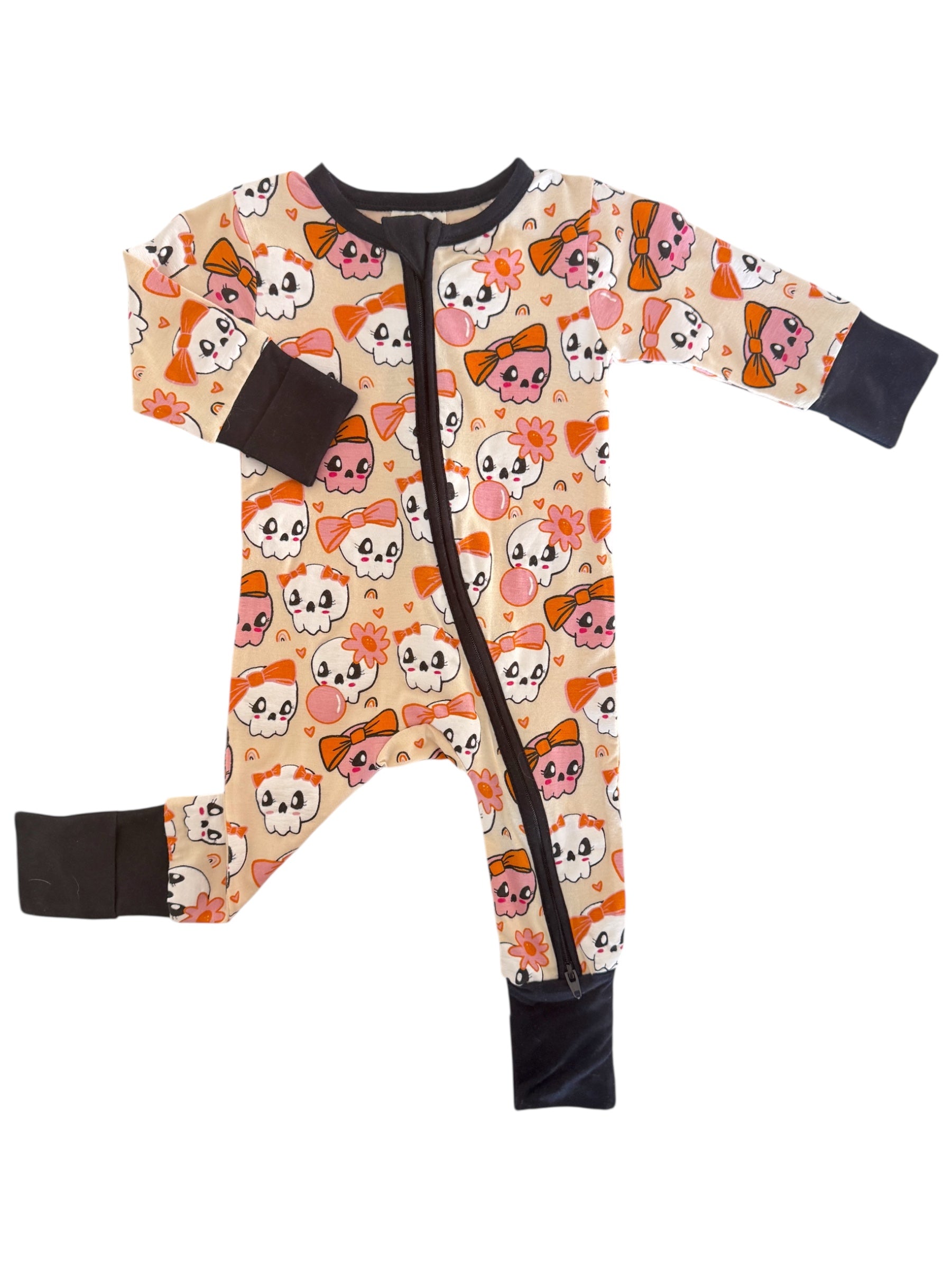 Toddler onesie featuring a playful skull and bow pattern in pastel colors on a cream background.