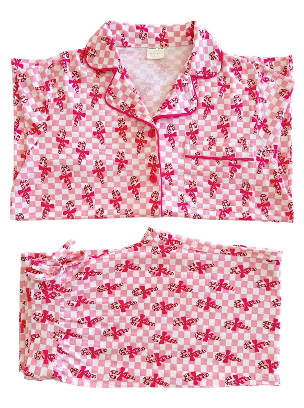 Pink and white checkered pajamas with candy cane and bow patterns, laid flat for display.