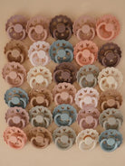 Colorful assortment of heart-shaped pacifiers arranged in a grid on a soft background.