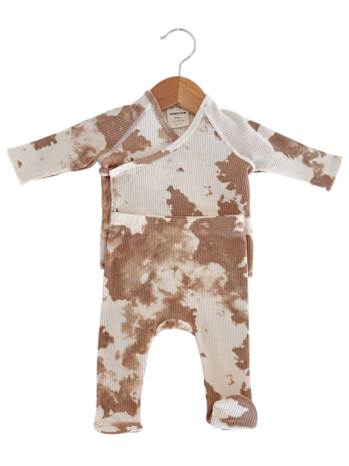 Brown and beige tie-dye newborn onesie hanging on a wooden hanger.