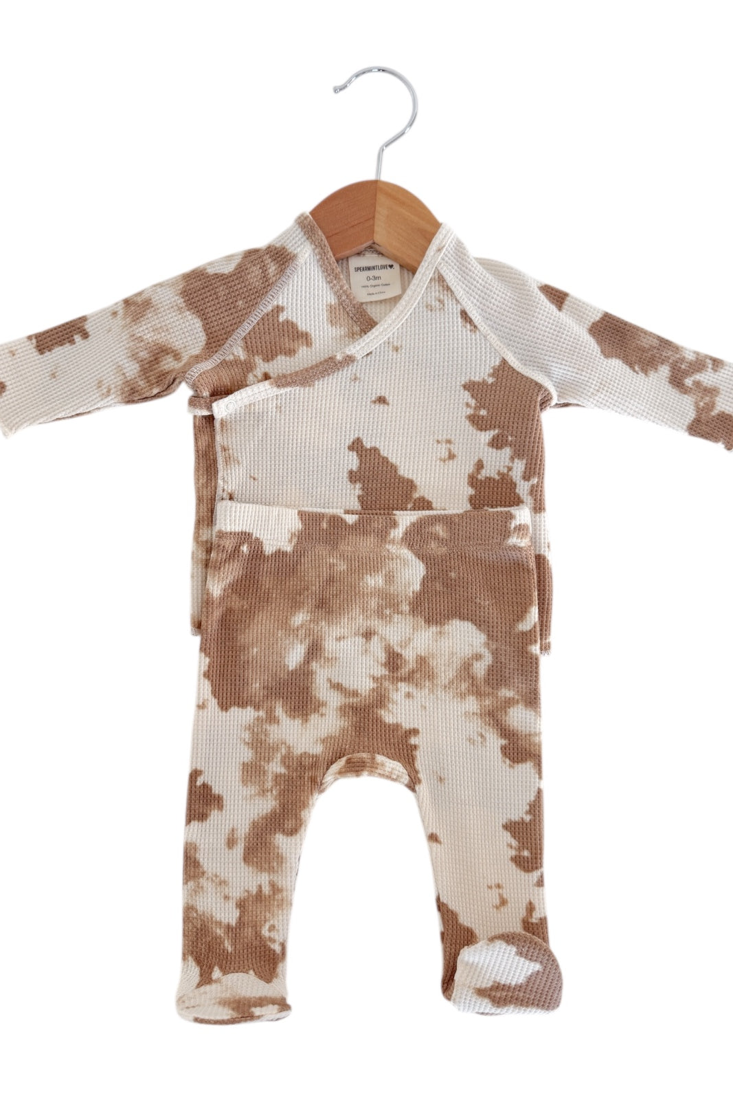 Brown and beige tie-dye newborn onesie hanging on a wooden hanger.