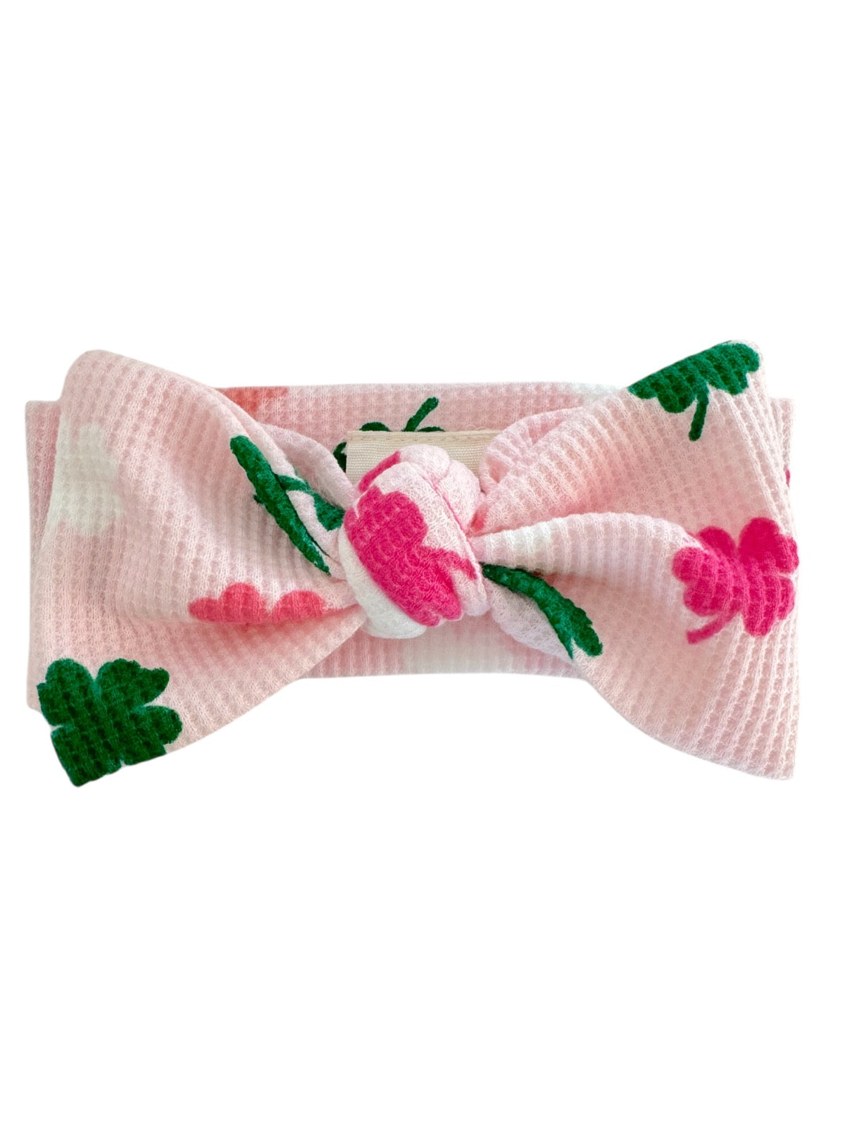 Pink floral headband featuring a large bow and green leaves, perfect for children.
