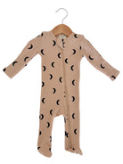 Beige baby onesie with black crescent moon patterns, displayed on a wooden hanger.