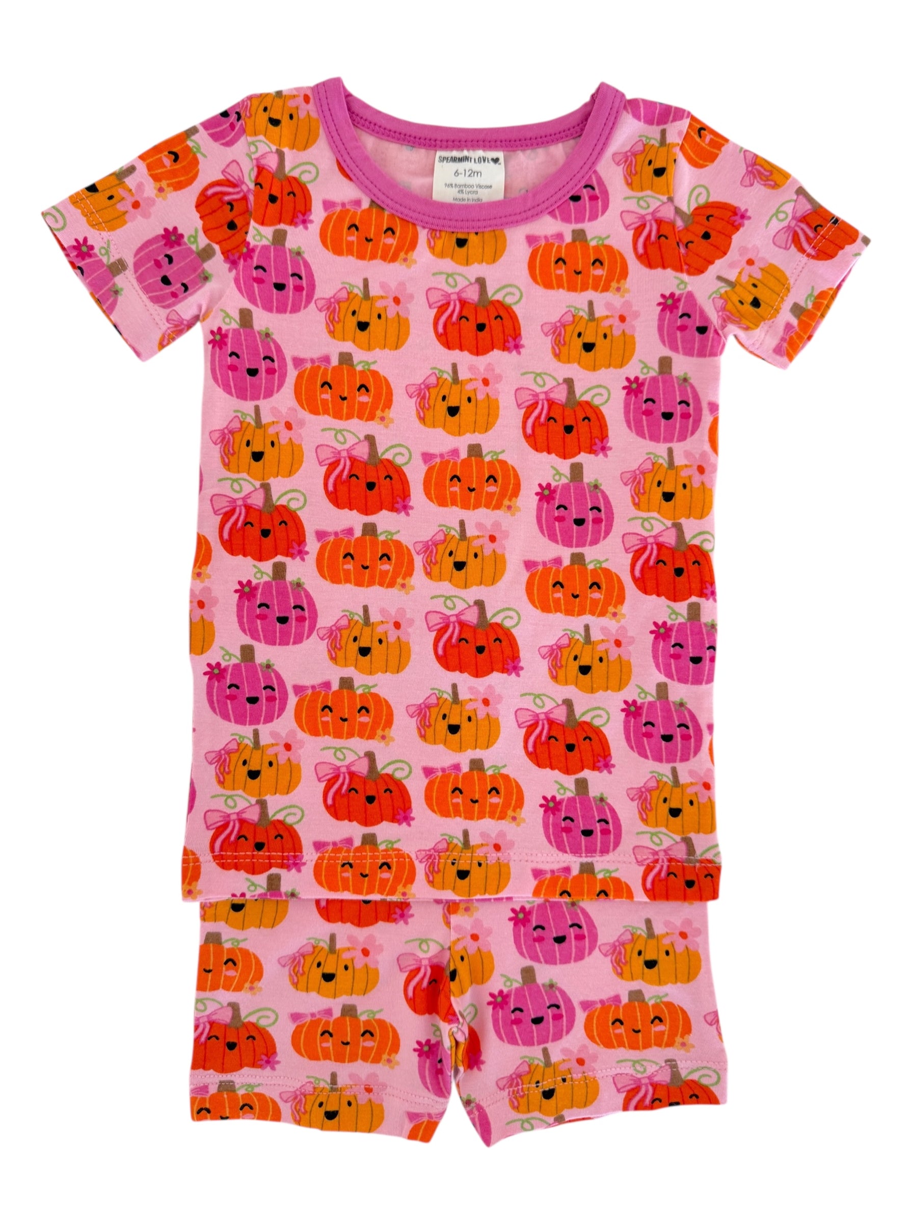 Pink toddler pajamas featuring a pattern of colorful, smiling pumpkins on a light pink background.