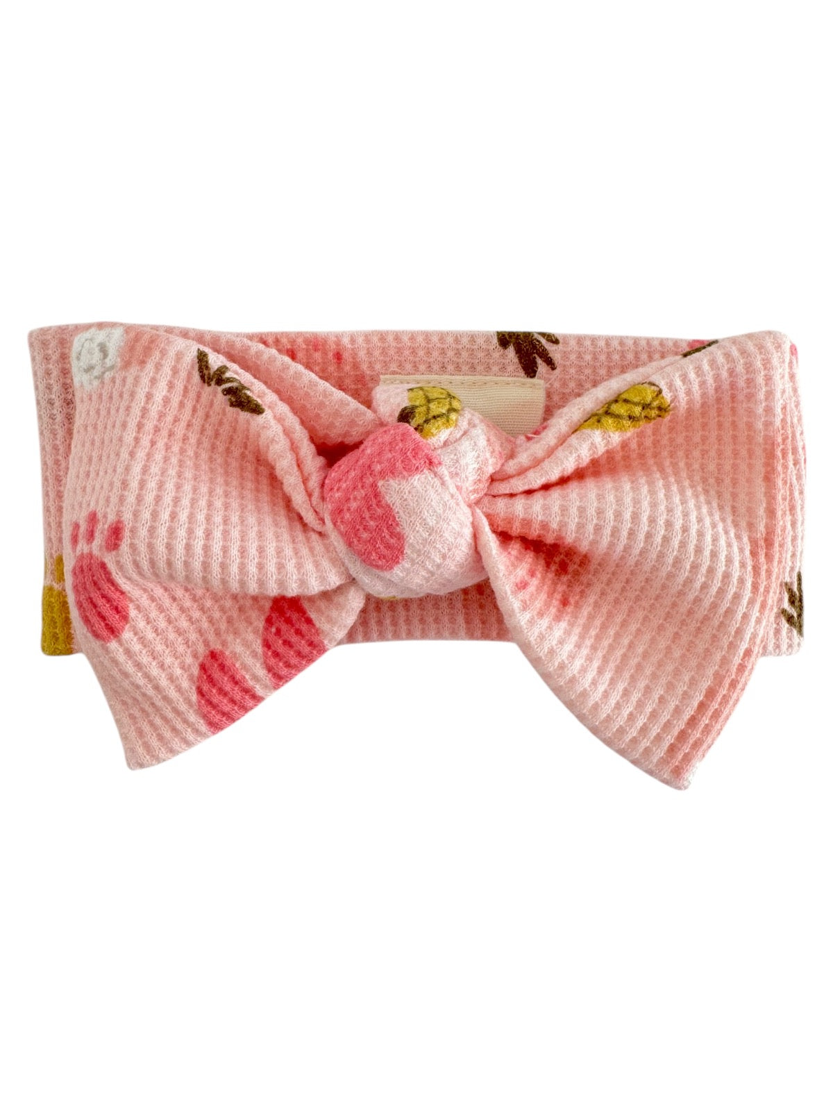 Pink headband with a large bow, featuring playful patterns of paw prints and pineapples.
