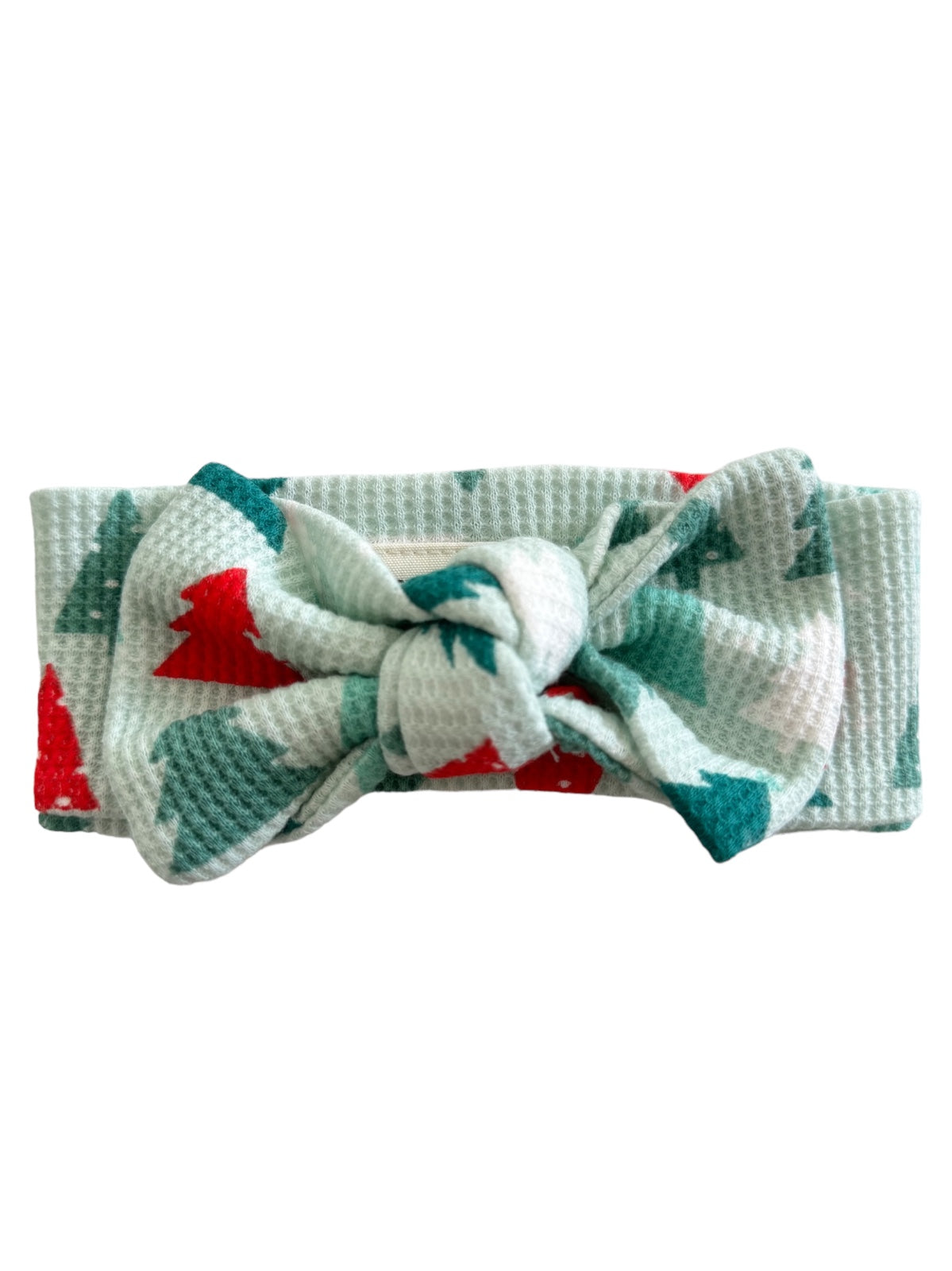 Waffle-knit headband with a bow, featuring a green and red Christmas tree pattern on a light background.