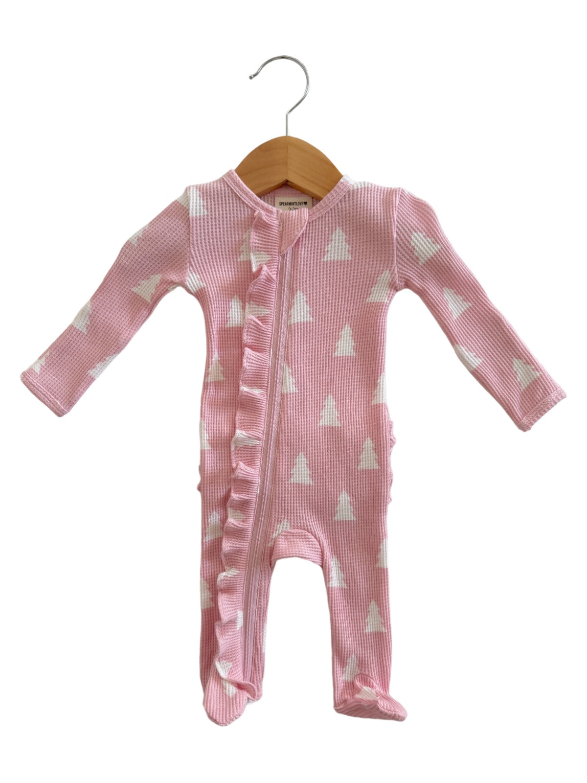 Pink long-sleeve baby onesie with white triangle patterns and ruffle detail, hanging on a wooden hanger.