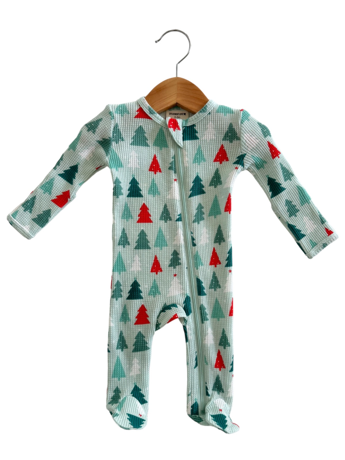 Children's onesie with green and red tree patterns, featuring a front zipper and long sleeves, displayed on a hanger.