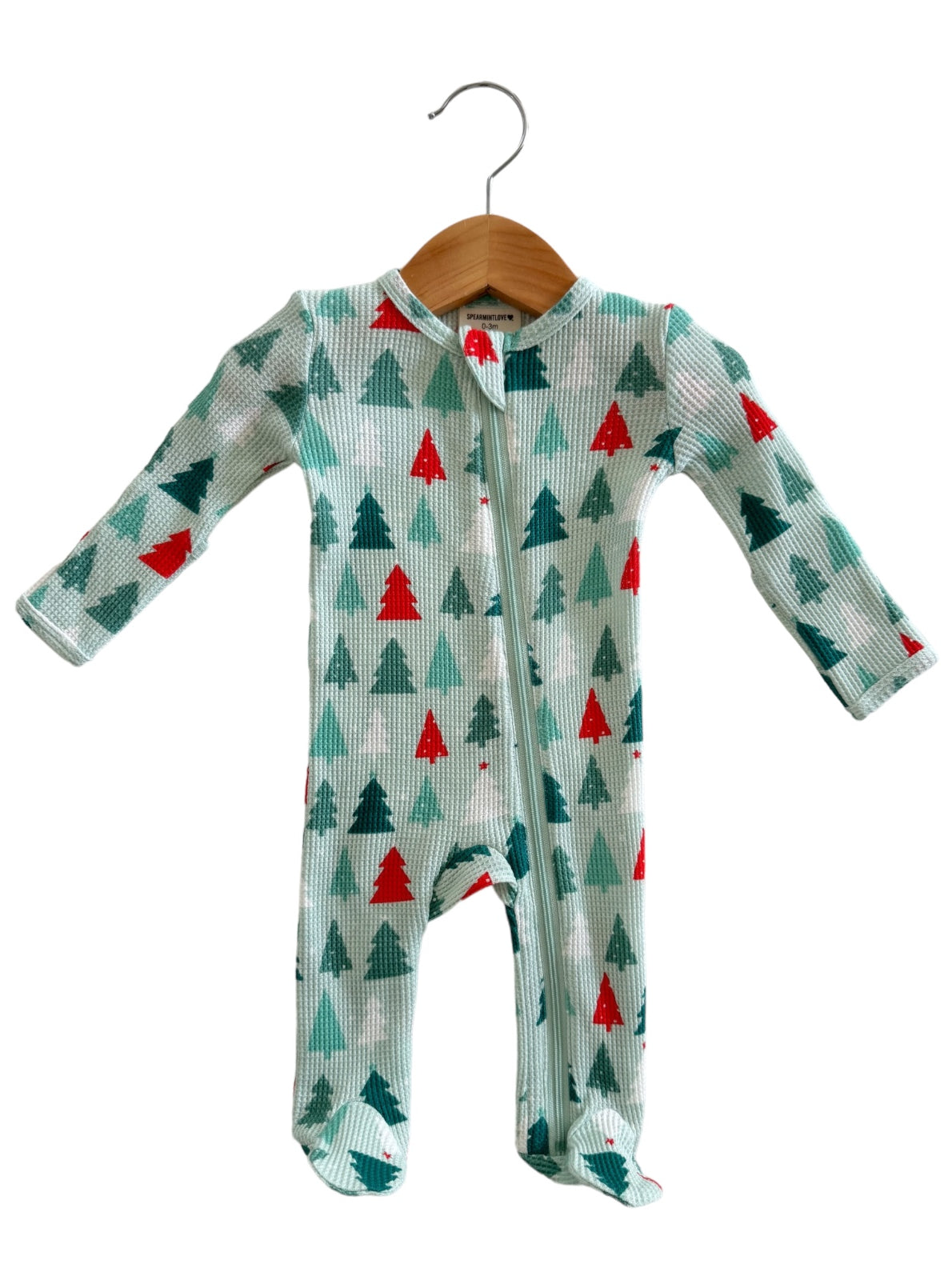 Children's onesie with green and red tree patterns, featuring a front zipper and long sleeves, displayed on a hanger.