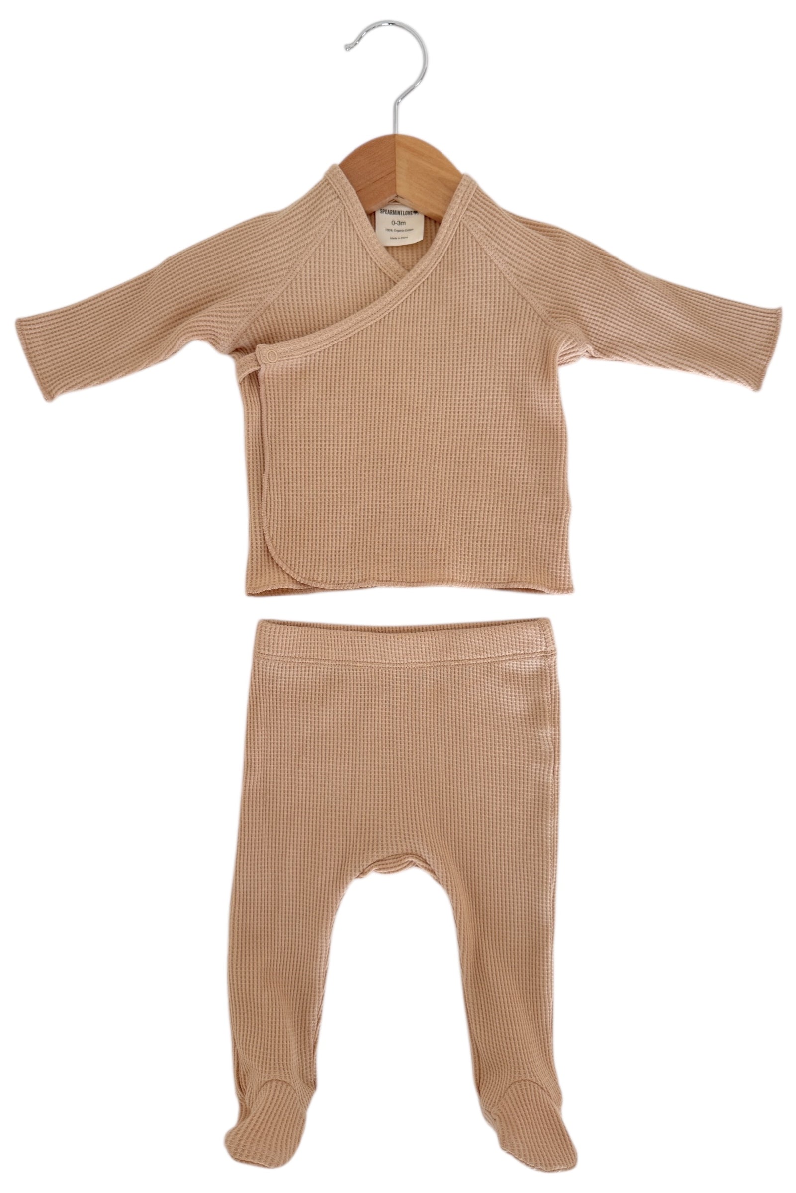 Beige infant wrap top and matching footed pants on a hanger, made from soft ribbed fabric.