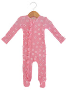 Pink baby onesie with white flowers and ruffles, hanging on a wooden hanger.