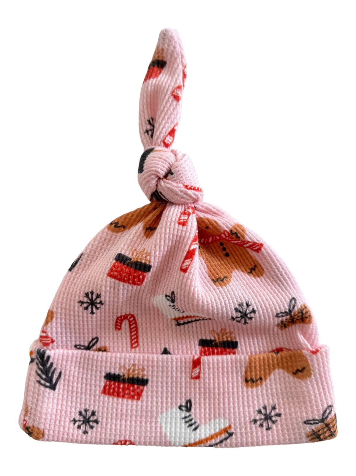 Pink baby hat with whimsical holiday patterns, including gingerbread, gifts, and candy canes.