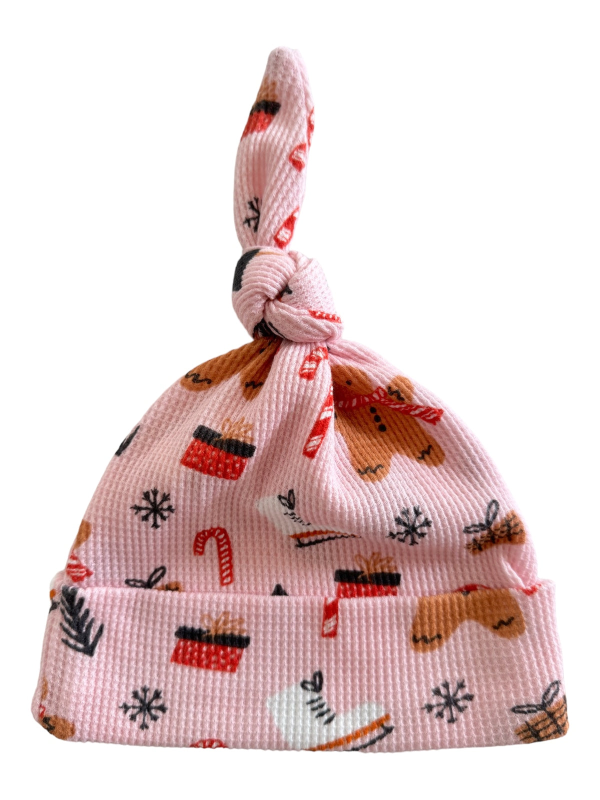 Pink baby hat with whimsical holiday patterns, including gingerbread, gifts, and candy canes.