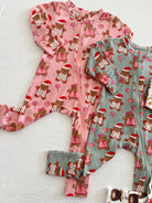 Two holiday-themed children's onesies in pink and green, featuring gingerbread figures and candy designs.