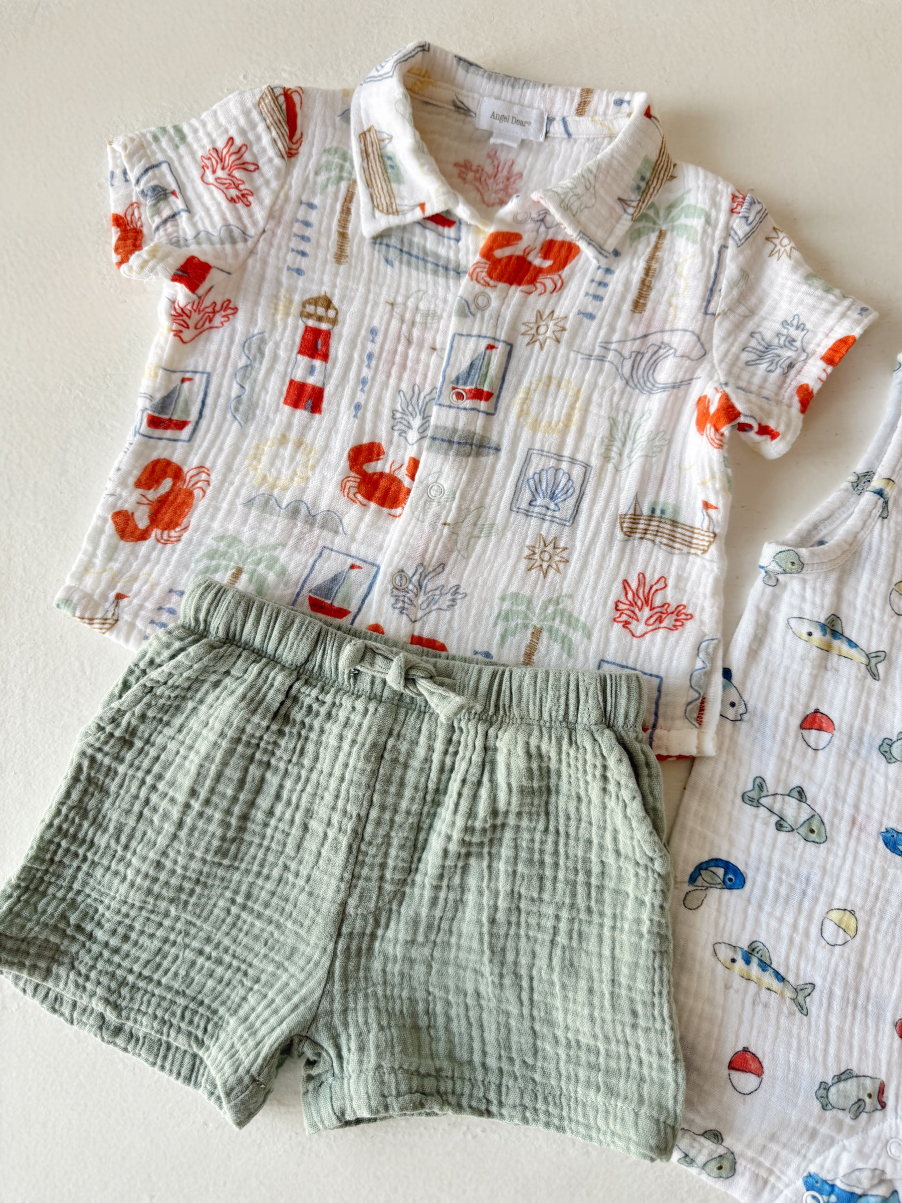 Colorful kids' outfit featuring a beach-themed shirt and soft green shorts, displayed on a light background.