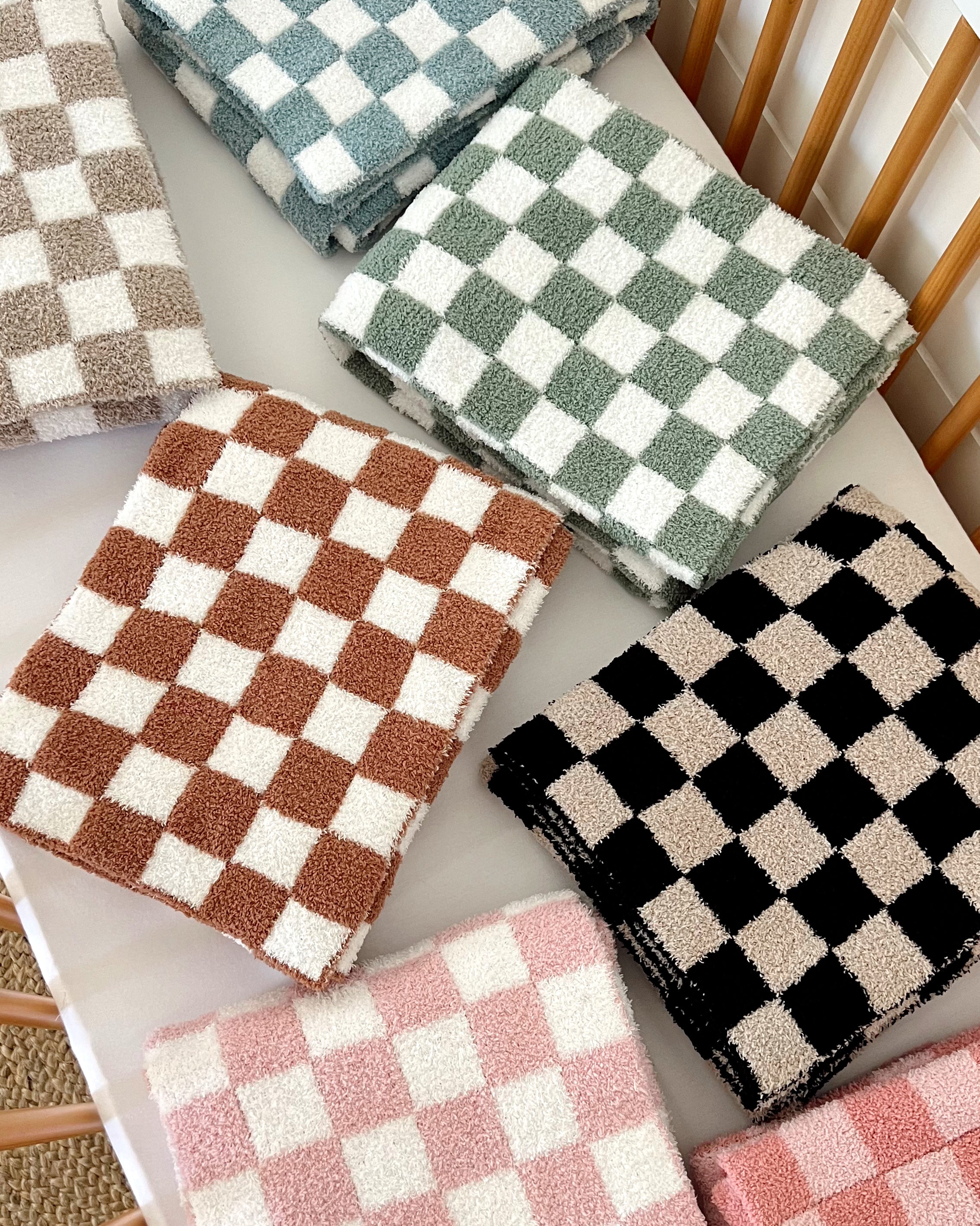 Stacked checkered towels in various colors, including brown, green, blue, pink, and black on a white table.