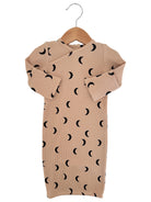 Beige ribbed baby dress with black crescent moon patterns, hanging on a wooden hanger.