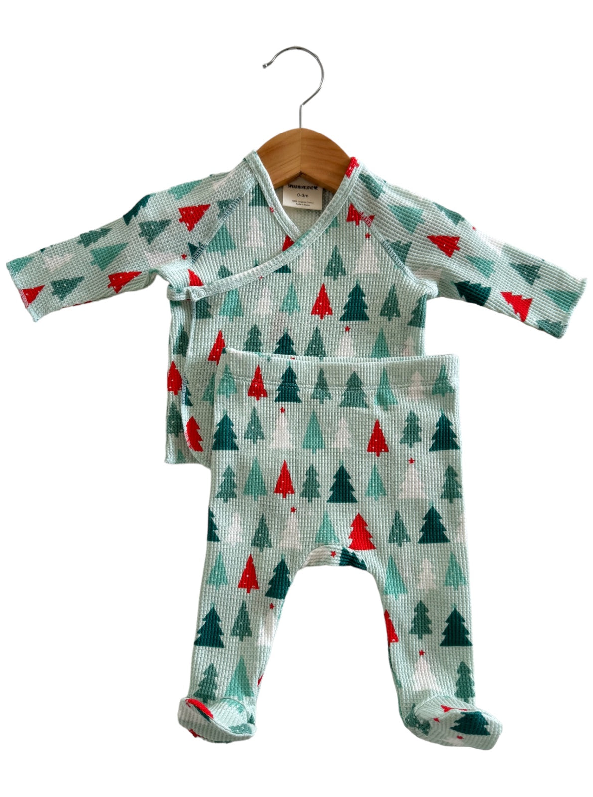 Light blue baby outfit featuring trees and stars, hanging on a wooden hanger. Ideal for cozy, festive occasions.