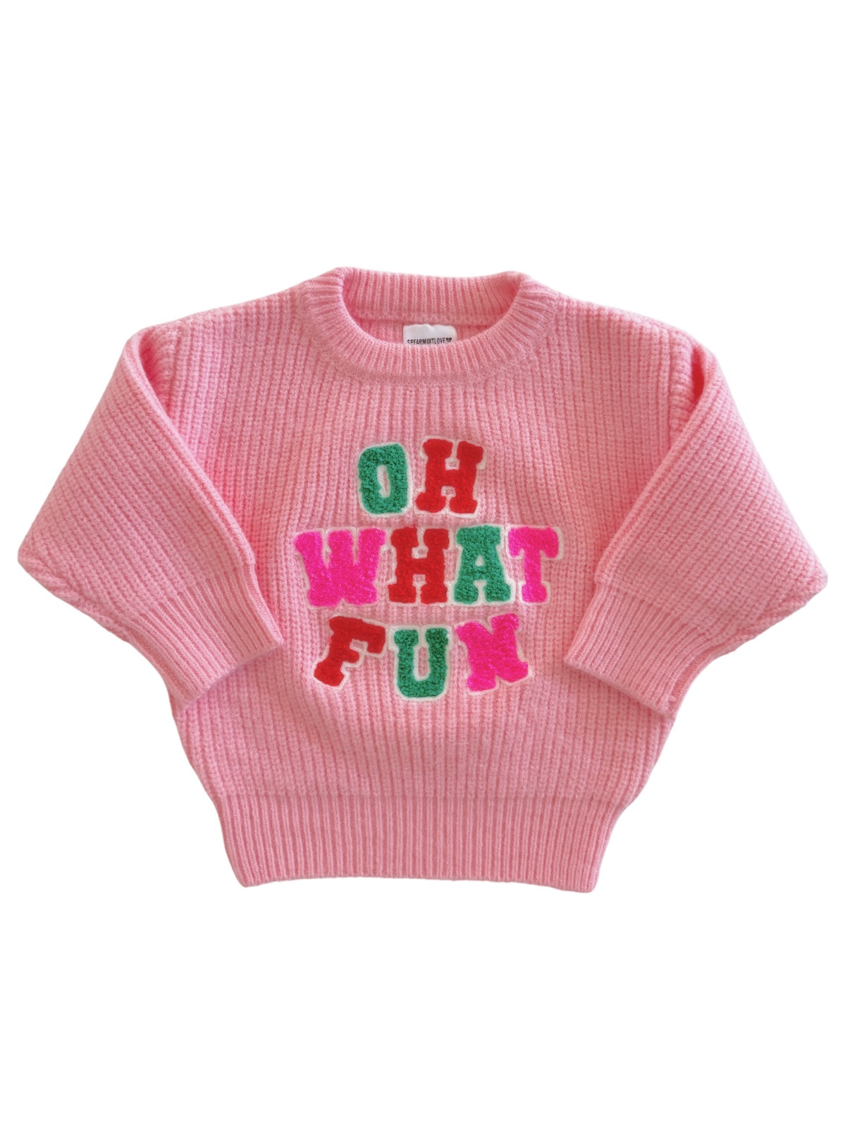 Pink sweater with colorful "OH WHAT FUN" text, featuring a cozy ribbed design and oversized fit.