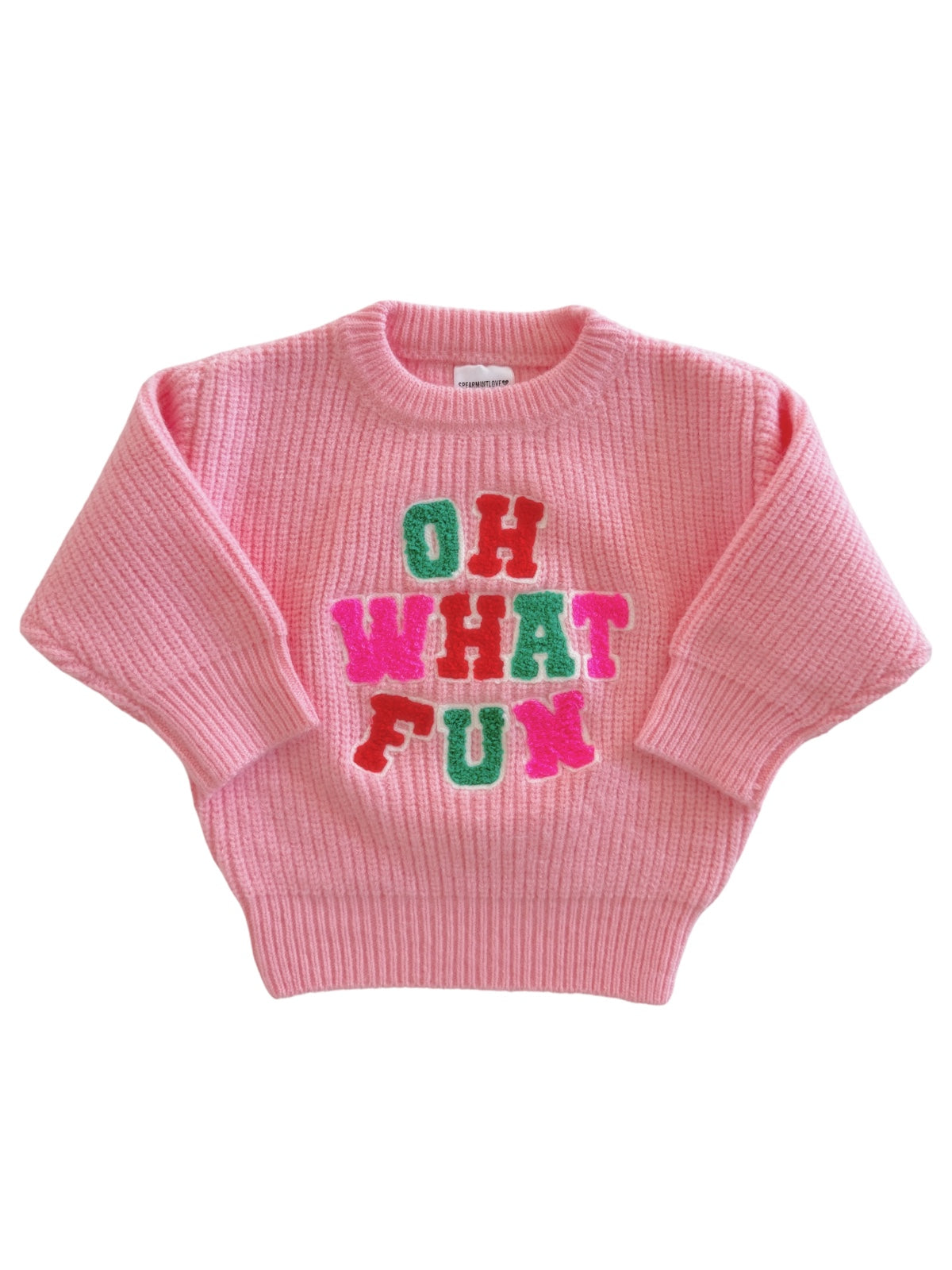 Pink sweater with colorful "OH WHAT FUN" text, featuring a cozy ribbed design and oversized fit.