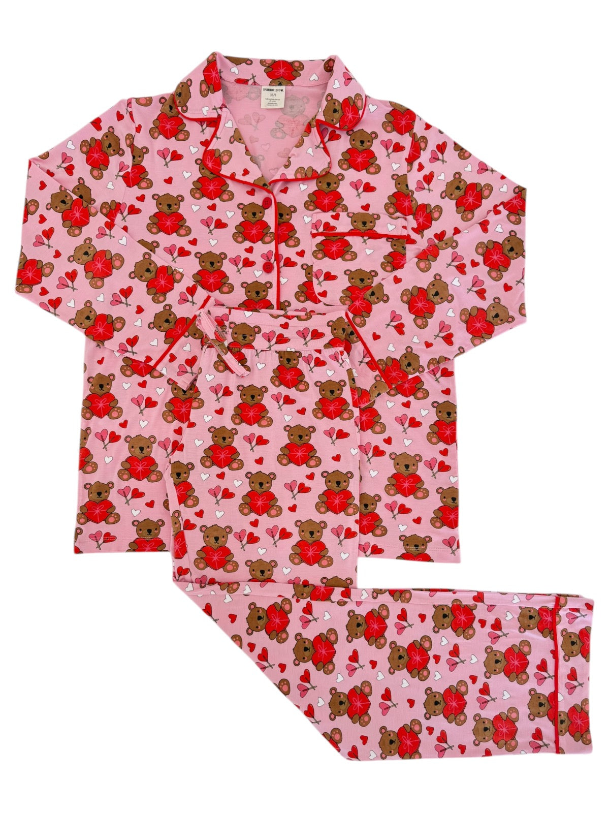 Pink pajama set featuring bears and hearts, perfect for cozy nights. Includes a button-up top and matching pants.