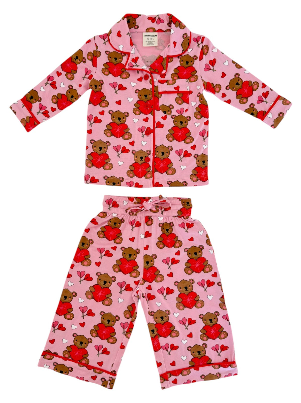 Pink children's pajama set featuring teddy bears and hearts in a playful pattern.