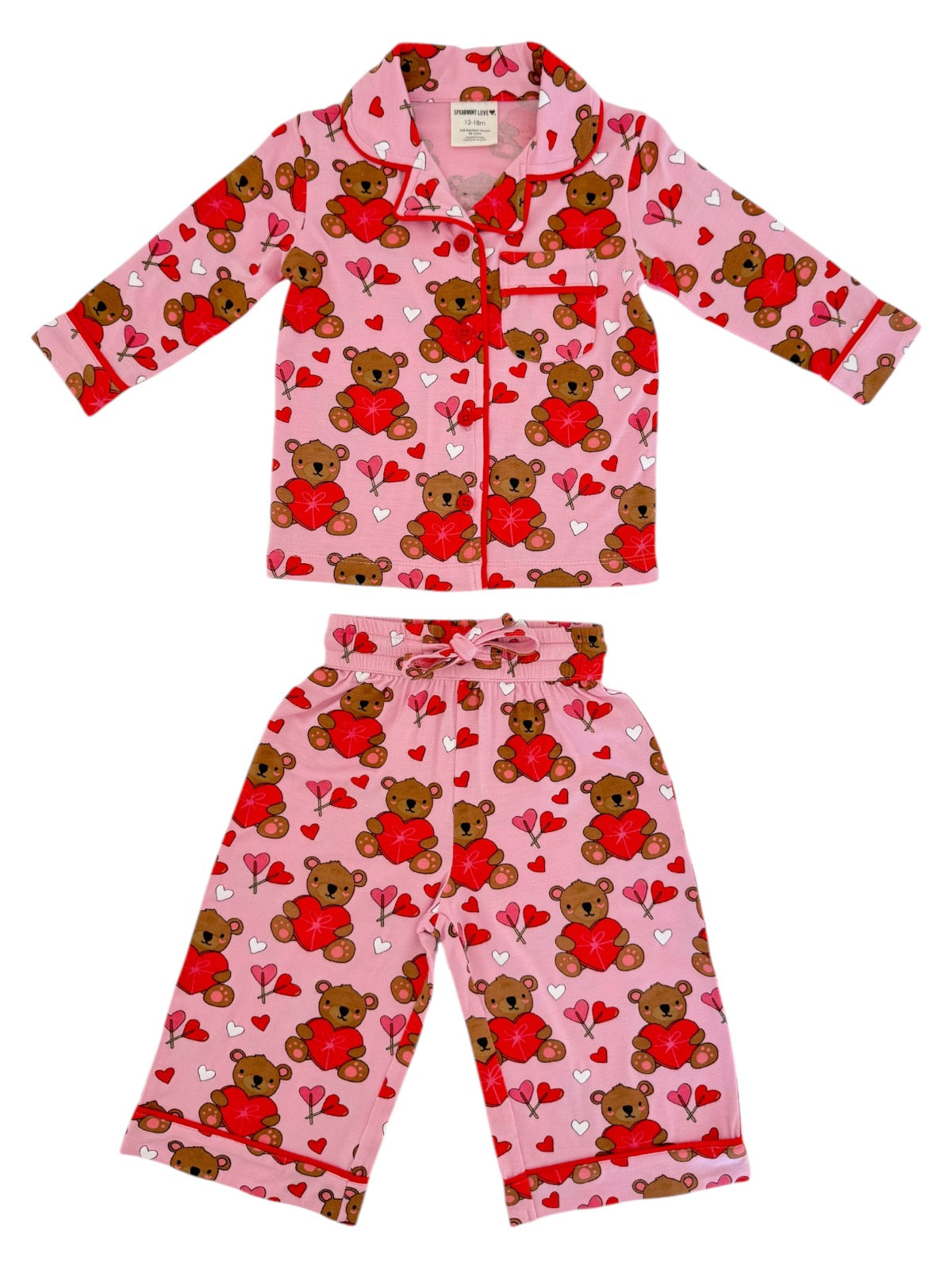 Pink children's pajama set featuring teddy bears and hearts in a playful pattern.