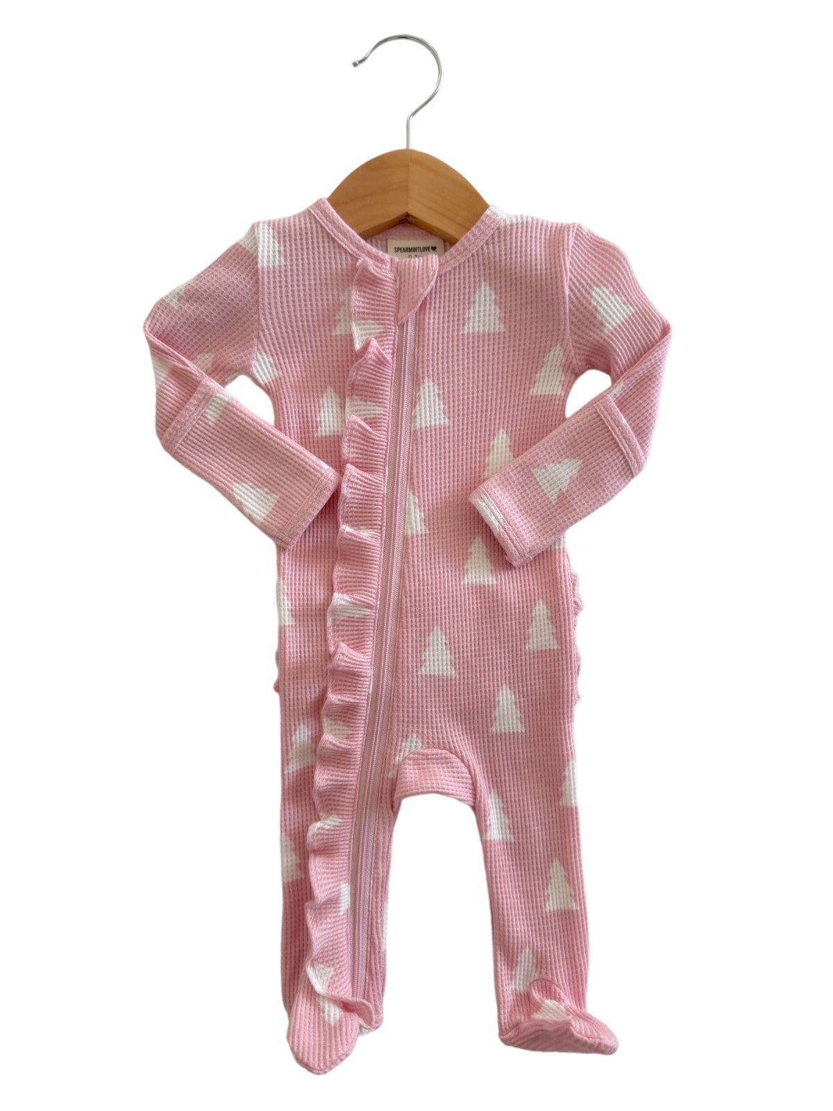 Pink children's onesie with white triangle patterns and ruffled edges, hanging on a wooden hanger.