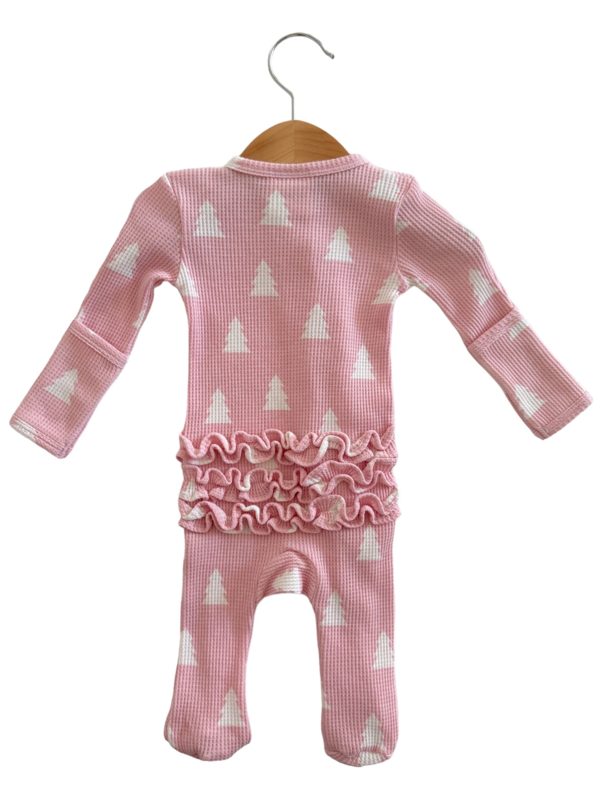 Pink baby onesie with white tree patterns and ruffle detail, hanging on a wooden hanger.