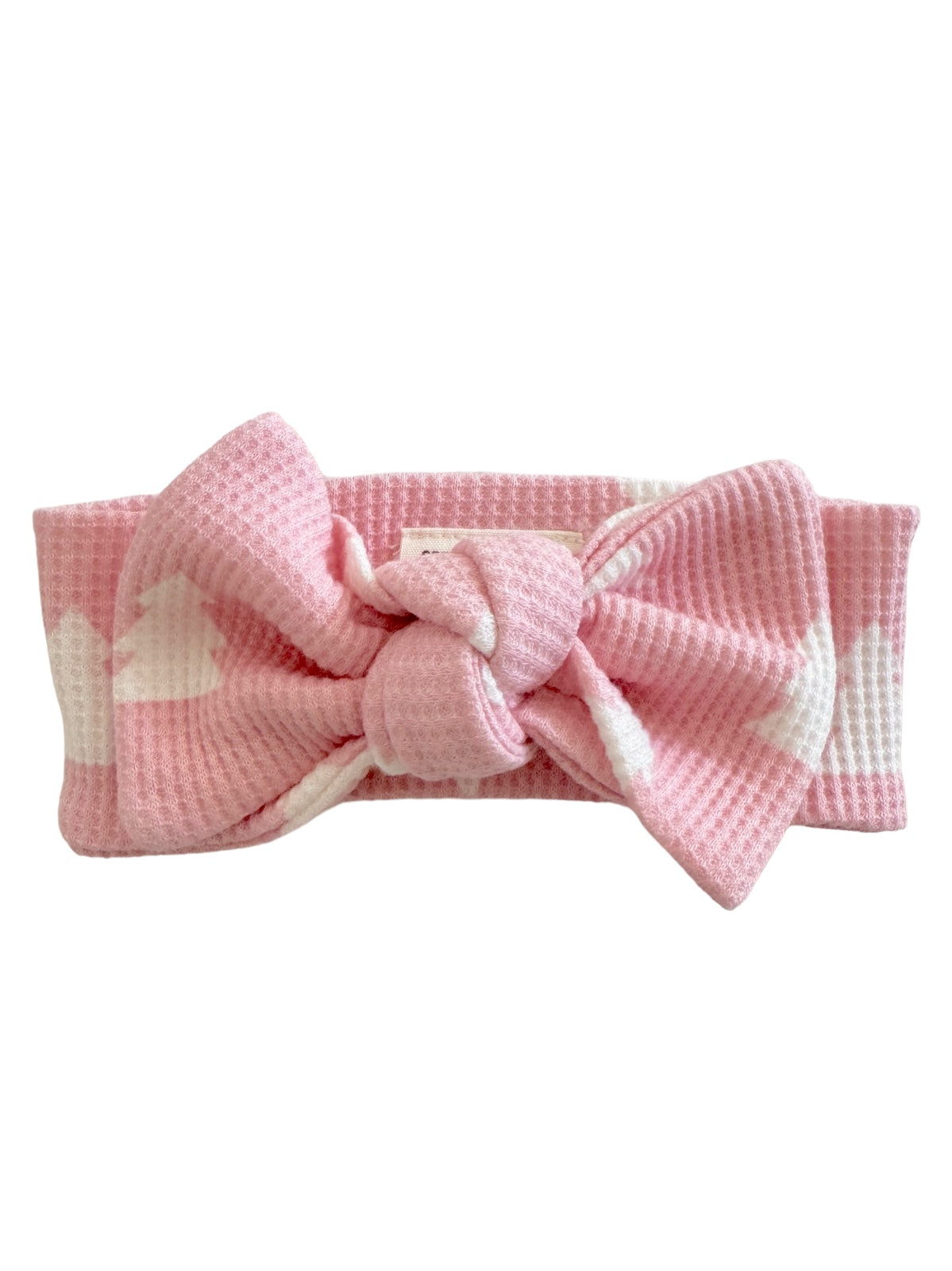 Pink headband with a knotted bow design, featuring a textured fabric and heart patterns.