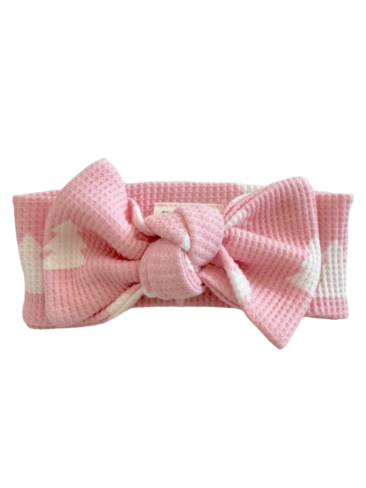 Pink headband with a knotted bow design, featuring a textured fabric and heart patterns.