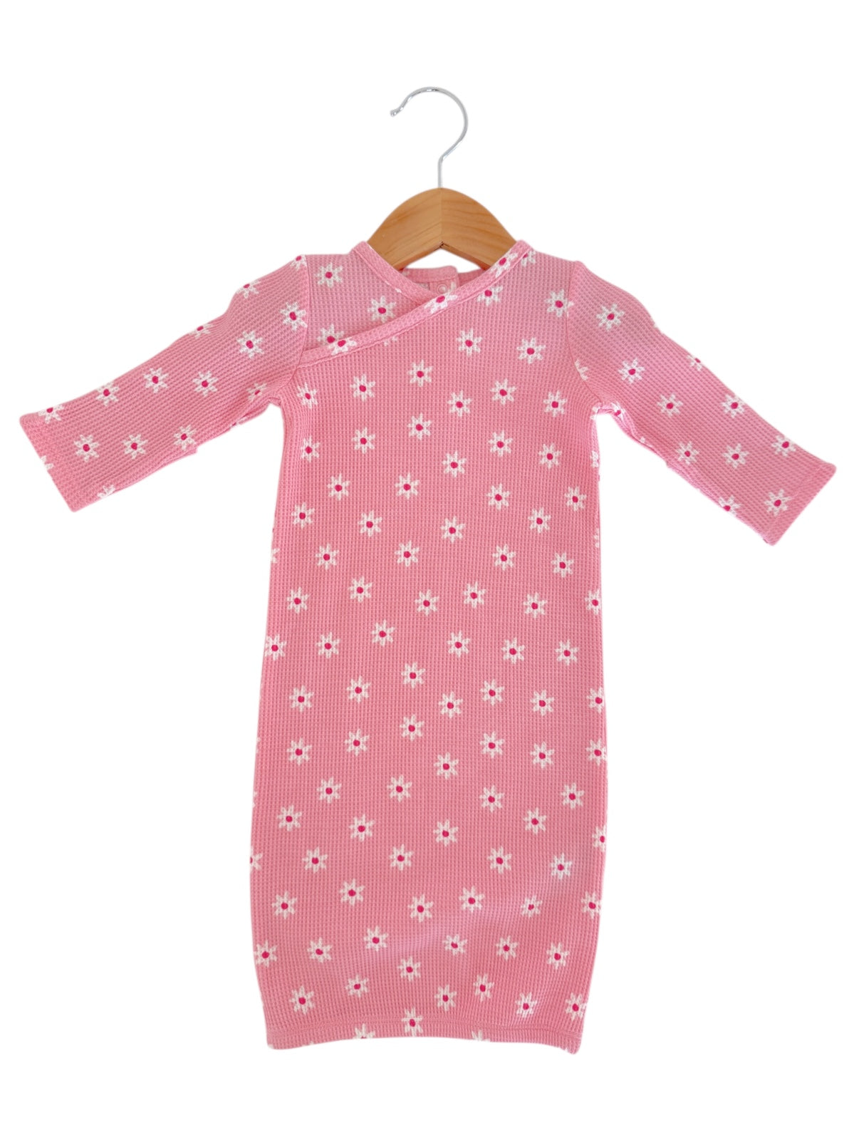 Pink baby dress with white floral pattern, displayed on a wooden hanger against a white background.