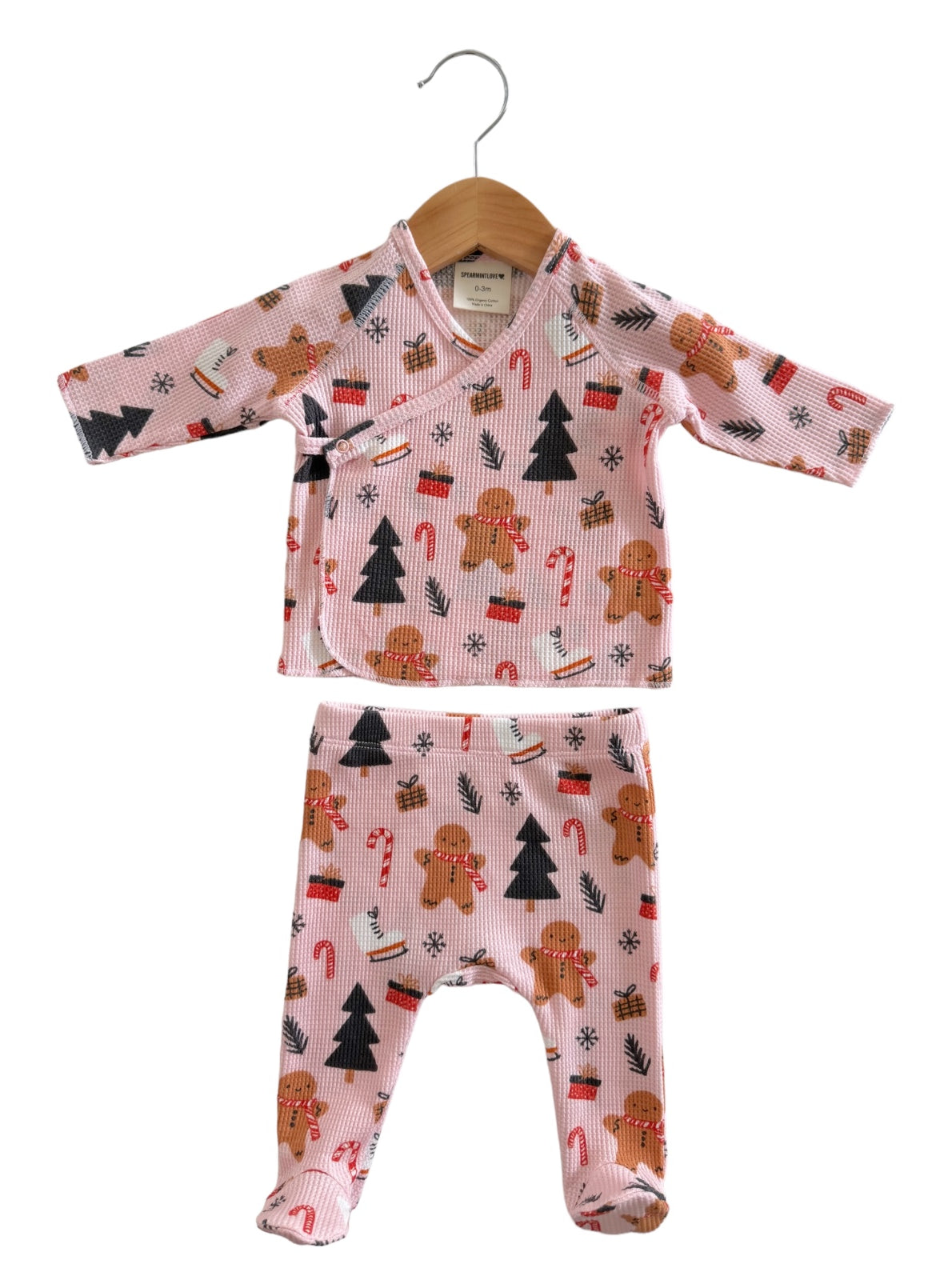 Pink baby outfit with gingerbread, candy canes, and trees, featuring a wrap top and matching pants.