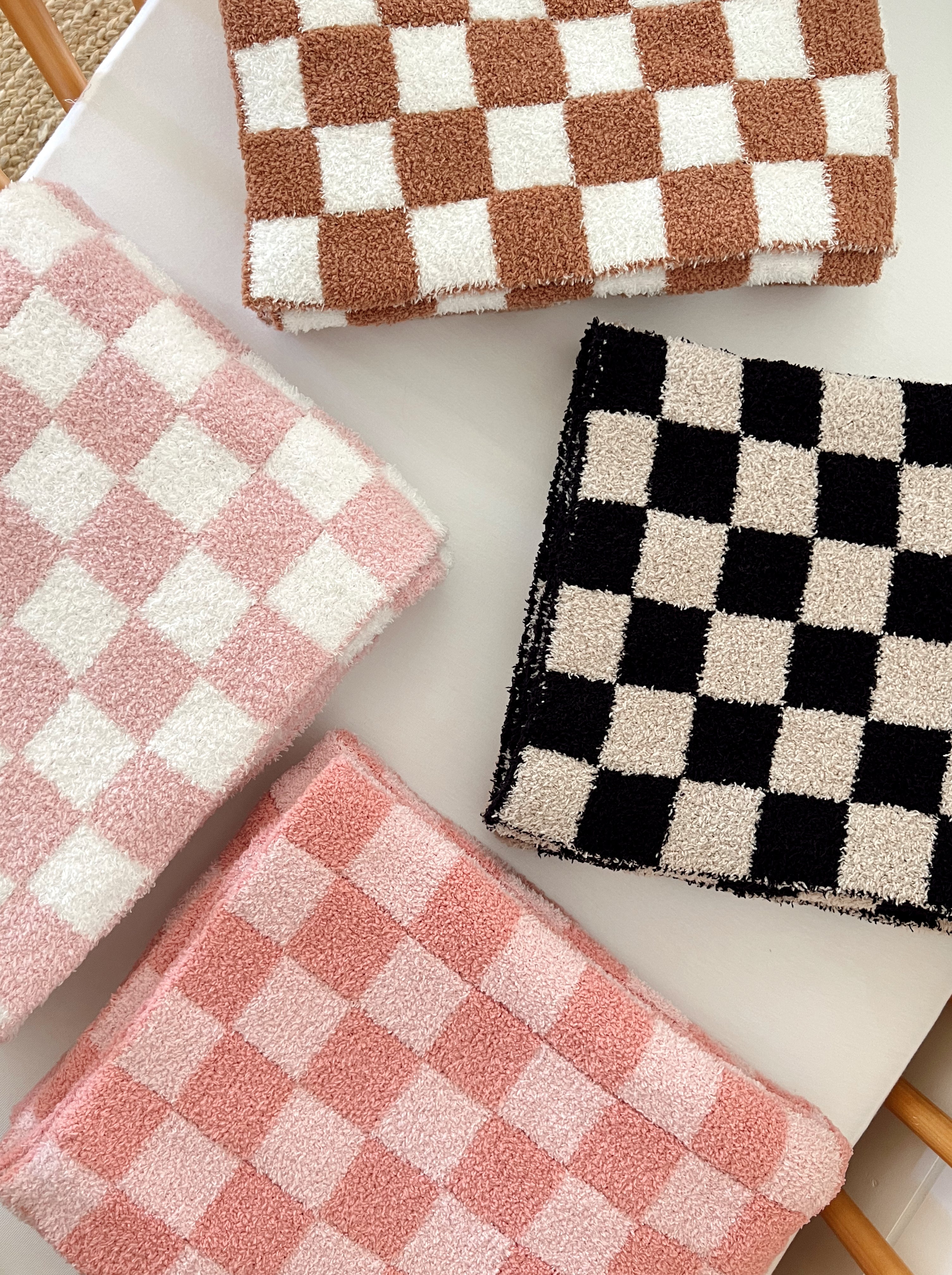 Colorful checkered towels in pink, brown, and black stacked on a white surface.