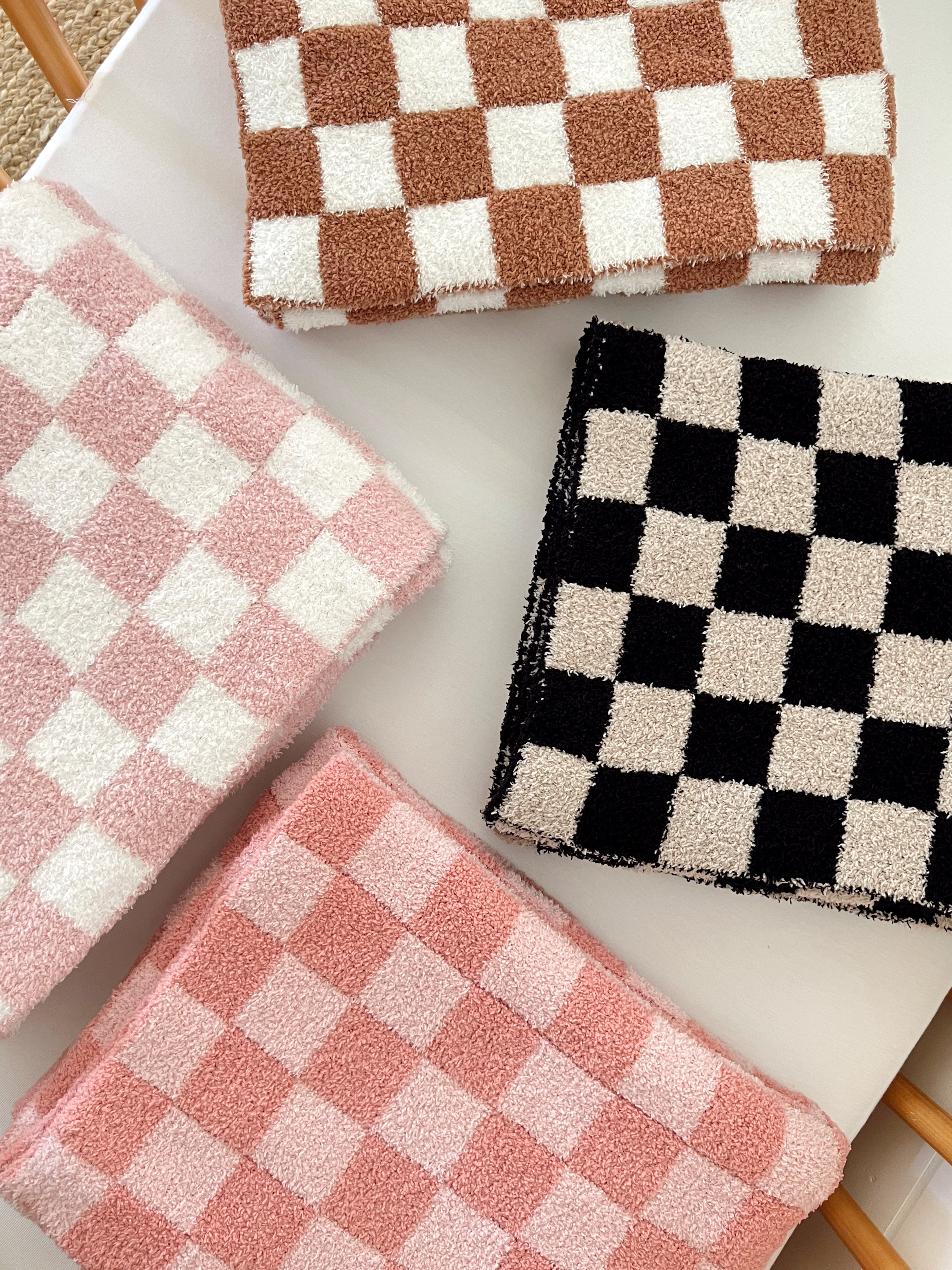 Colorful checkered towels in pink, brown, and black stacked on a white surface.