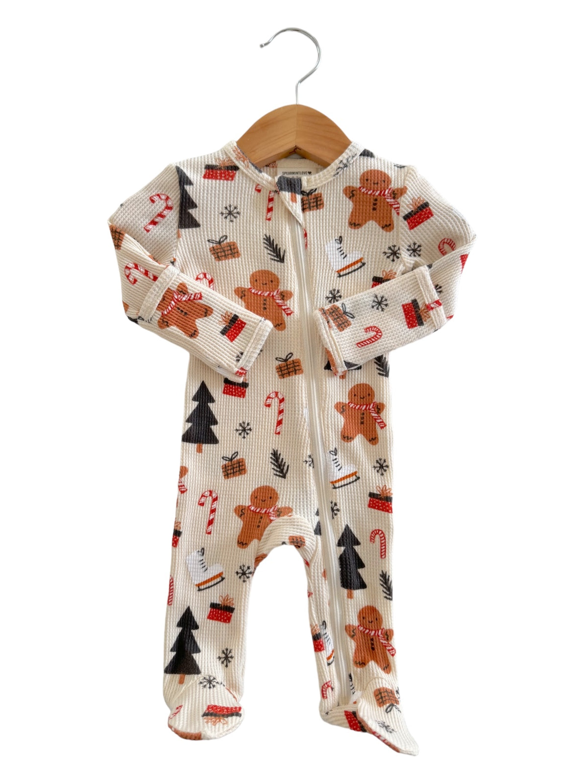Holiday-themed baby onesie with gingerbread men, candy canes, and pine trees on a light background.