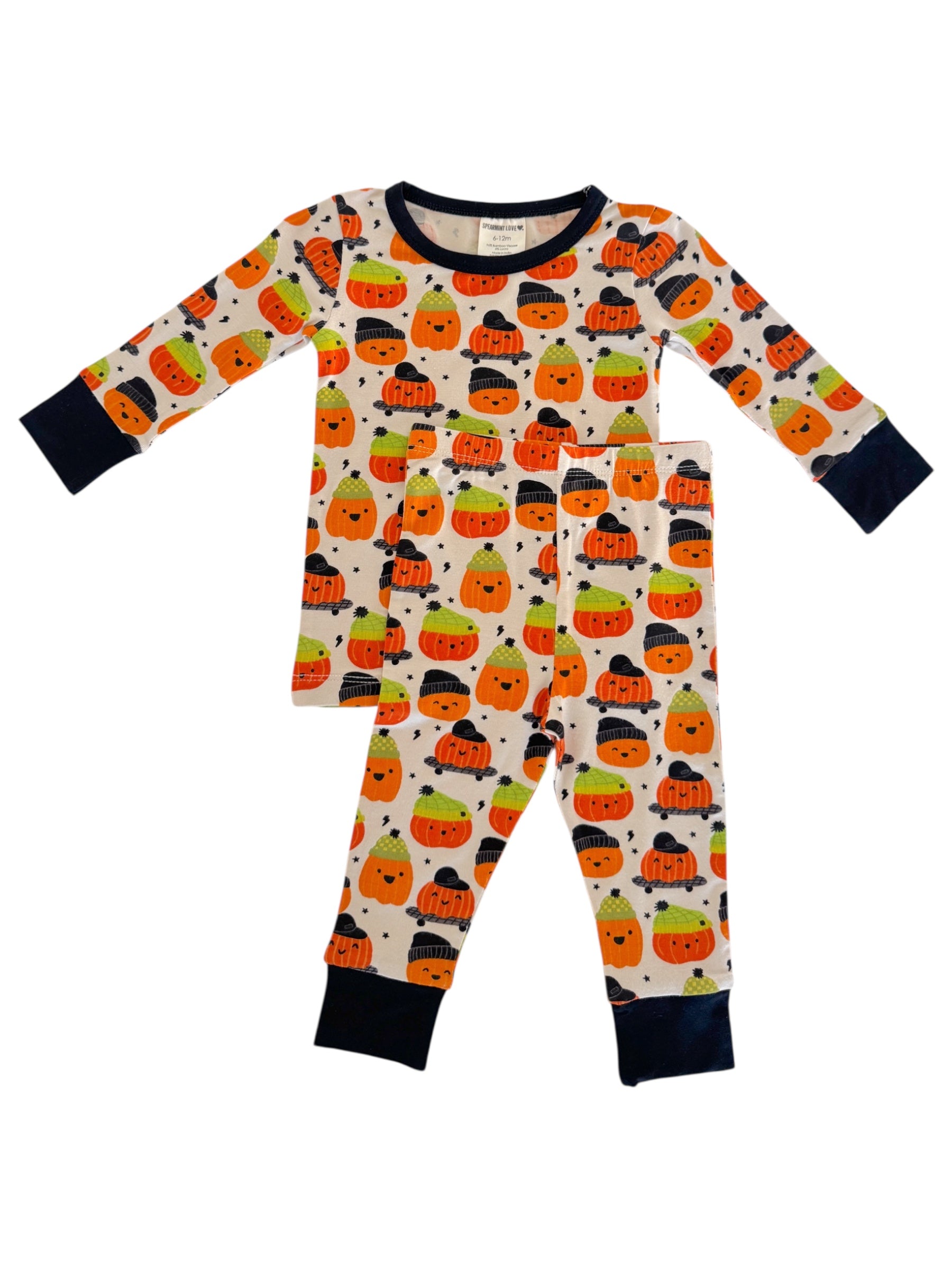 Children's pajama set featuring colorful smiling pumpkins on a cream background with navy blue trim and cuffs.